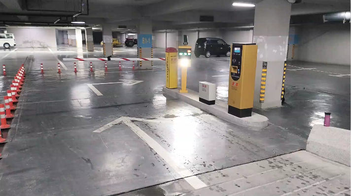 Real car park entry with ticket dispenser, boom barrier and lane cones installed by ASG Systems