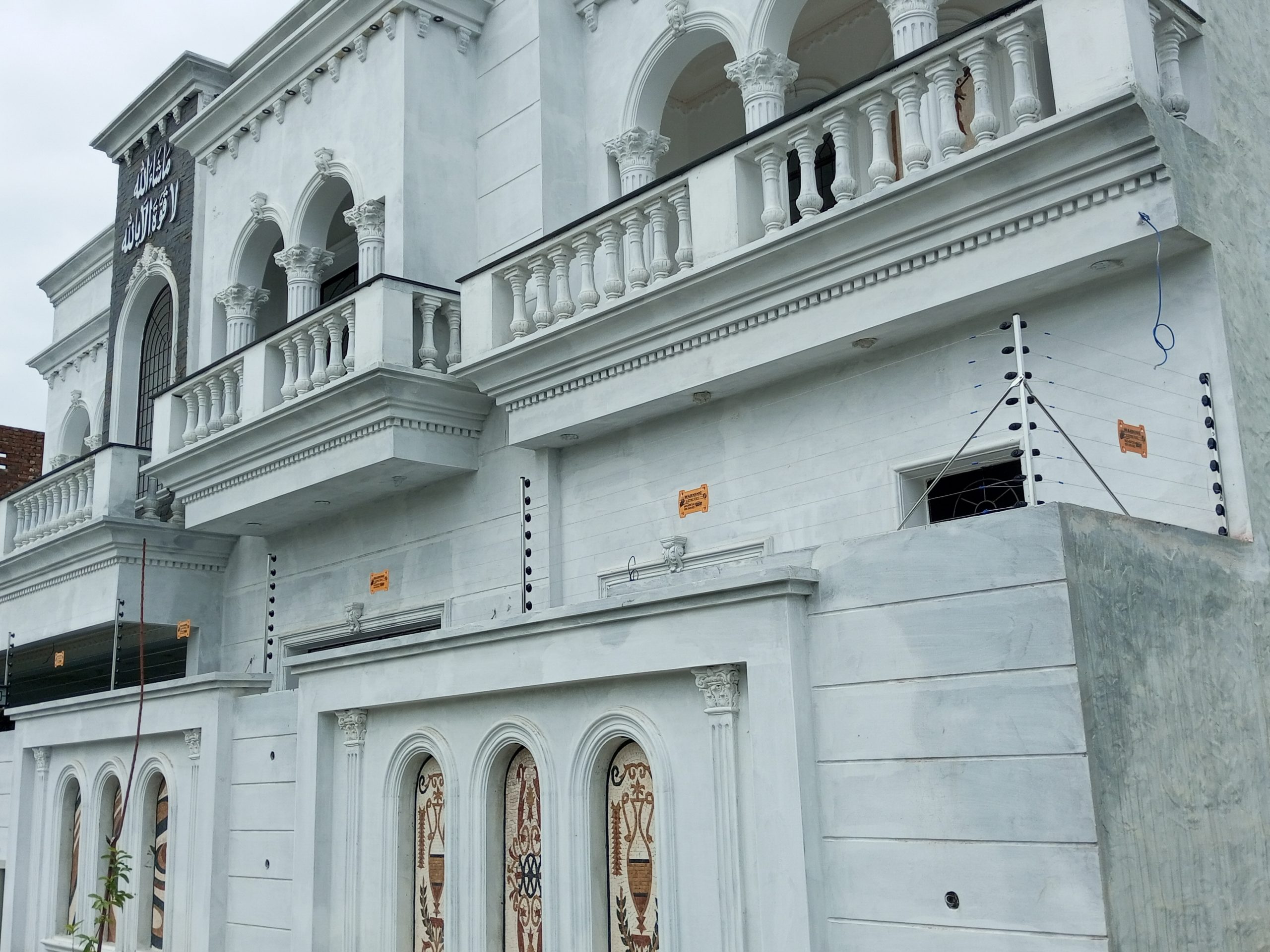 Electric fence installed on the roof line and boundary of a white luxury villa