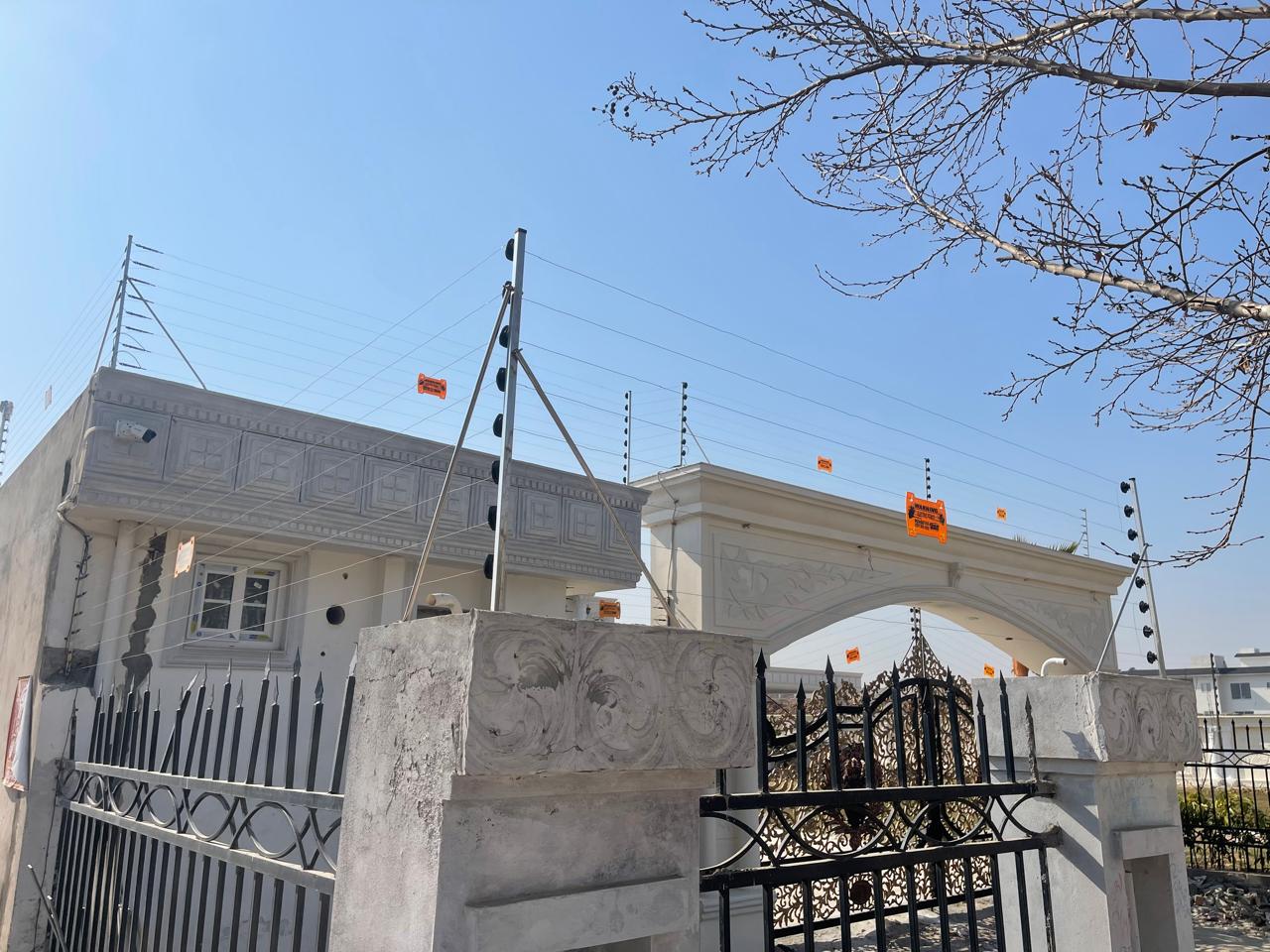 Electric fence on the boundary wall and gate of a white house