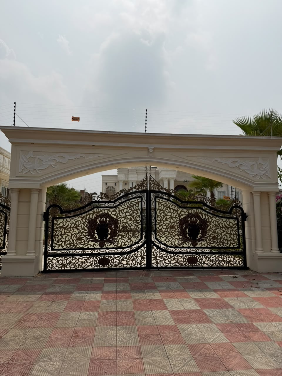 Electric fence above an ornate arched main gate and entrance of a house