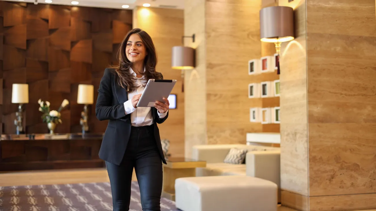 Hotel housekeeping manager checking live room status on a tablet in a hotel lobby