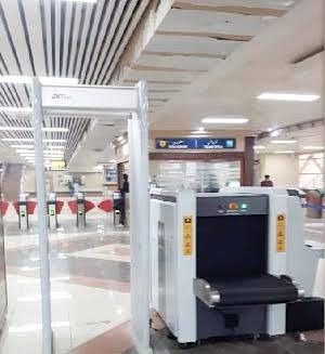Walk-through metal detector gate and baggage X-ray scanner installed at an Orange Line Metro station in Lahore