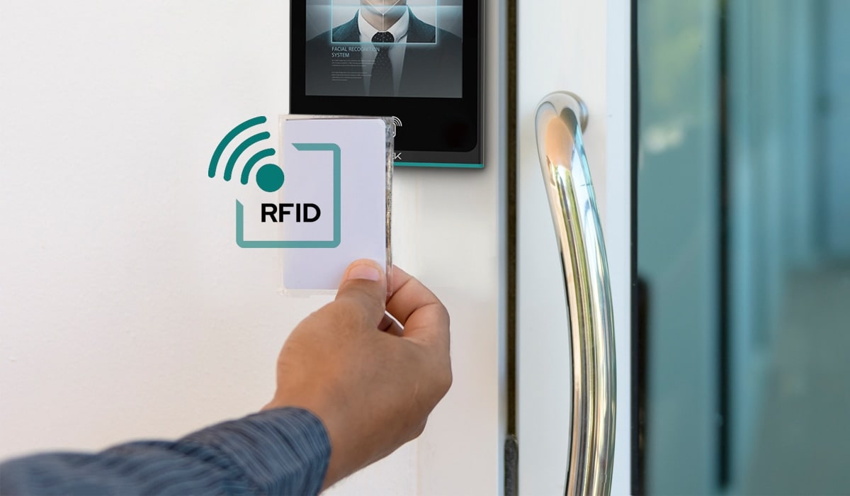 Hand holding an RFID card to an access control reader at a glass office door