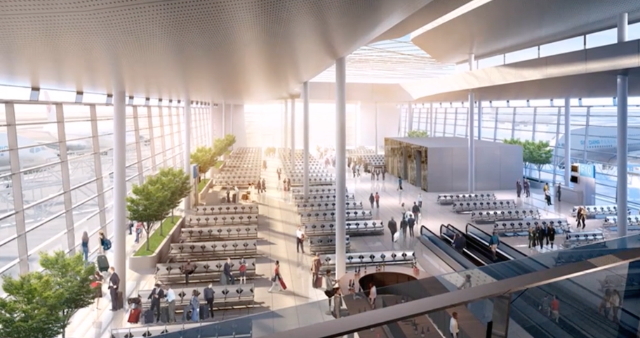 Bright modern terminal hall with a daylit roof, indoor trees and travellers