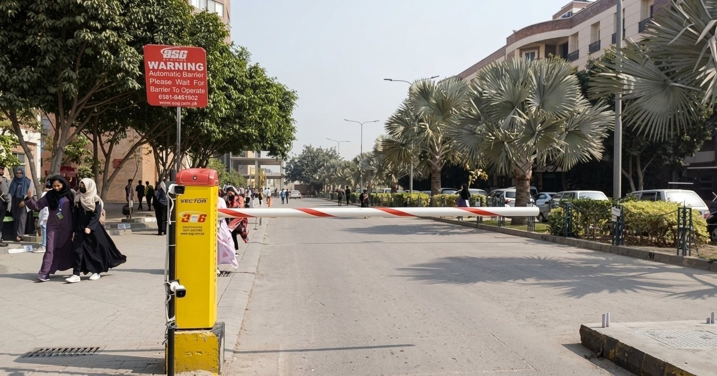 Campus checkpoint with guard booths and boom barriers on the main boulevard at the University of Lahore